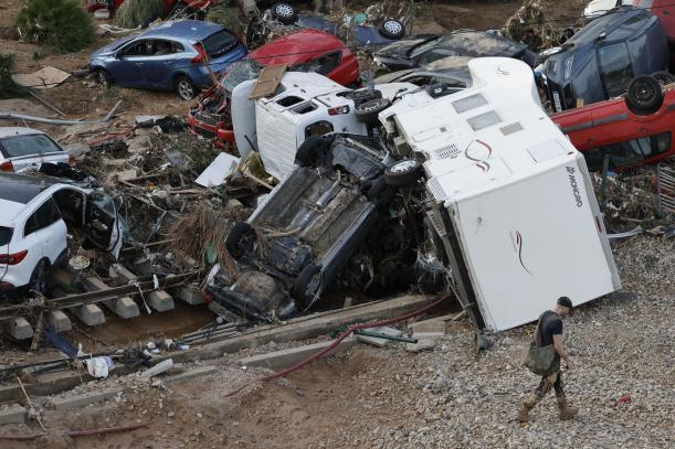 ALFAFAR (VALENCIA), 01/11/2024.- Un hombre camina entre los vehículos amontonados sobre las vías del tren en Alfafar (Valencia), este viernes. La búsqueda de desaparecidos, la identificación de víctimas mortales, las tareas de limpieza y la reparación de infraestructuras continúan tres días después de las inundaciones que han asolado la provincia de Valencia, en una jornada en la que el Gobierno envía a 500 militares más, que se sumarán a las 1.200 efectivos de la Unidad Militar de Emergencias (UME), para actuar en Utiel, Requena, Riba-roja, Torrent, Paiporta y Algemesí. EFE/ Kai Försterling