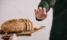 cropped view of woman holding cutting board with sliced bread near man with gluten intolerance