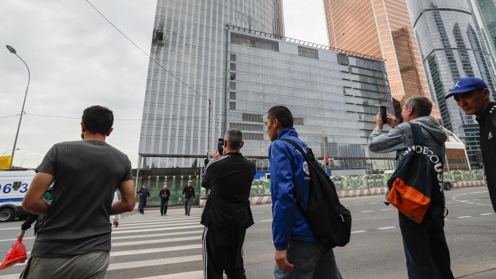 eople walk past a damaged building in the Moscow-City business center after a drone reportedly fell, in Moscow,