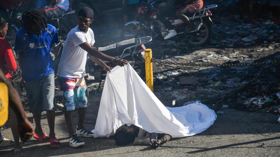 ATENCIÓN EDITORES: CONTENIDO GRÁFICO EXPLÍCITO - AME9715. PUERTO PRÍNCIPE (HAITÍ), 18/03/2024.- Un hombre cubre el cadáver de una persona en el suelo este lunes, en Puerto Príncipe (Haití). Doce cadáveres fueron encontrados este lunes en Petion-Ville, en las colinas de Puerto Príncipe, en circunstancias aún por aclarar, como la identidad de las víctimas, que no se descarta sean miembros de bandas armadas abatidos por la Policía Nacional. Los cuerpos, entre ellos el de una mujer, fueron hallados dispersos en plena vía, en los alrededores de una zona dedicada al comercio informal de alimentos y otros productos. EFE/ Johnson Sabin