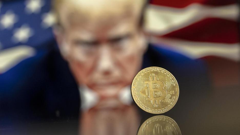 EA5586. BOGOTÁ (COLOMBIA), 05/12/2024.- Fotografía de archivo del 22 de noviembre del 2024 del símbolo de Bitcoin junto a una imagen del presidente electo de Estados Unidos, Donald Trump, en Lugano (Suiza). 'Un bitcóin viento en popa' es uno de los clics tecnológicos de la semana. Y es que el miércoles el bitcóin trepó la barrera de los 100.000 dólares, aupado por el entusiasmo de la elección de Donald Trump como presidente de Estados Unidos y la designación de Paul Atkins, un abogado abiertamente defensor de las criptomonedas, como futuro presidente de la Comisión de Bolsa y Valores (SEC), el principal organismo regulador de EE.UU. EFE/EPA/PABLO GIANINAZZI / ARCHIVO