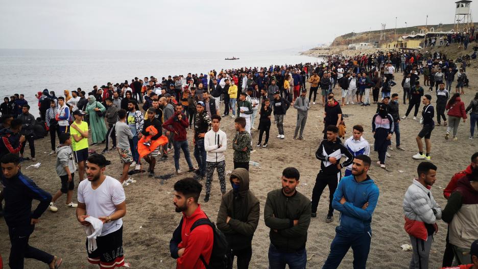 ***CORRECCIÓN. CORRIGE FUENTE Y FOTÓGRAFO*** GRAF9932. FNIDEQ (MARRUECOS), 18/05/2021.- Cientos de personas esperan en la playa de la localidad de Fnideq (Castillejos) para cruzar los espigones de Ceuta este martes en una avalancha de inmigrantes sin prec