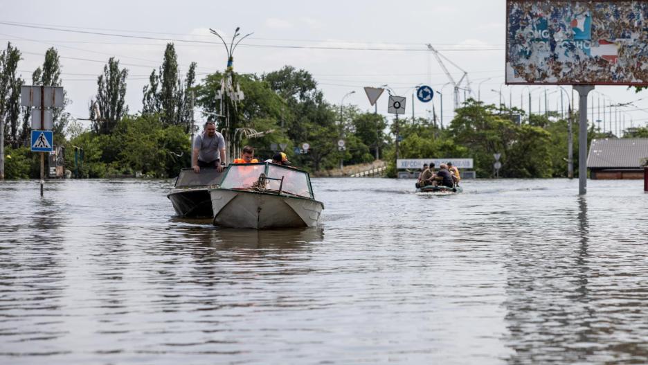 Residentes y trabajadores de los servicios de rescate usan barcas para moverse en una zona inundada de Jersón.