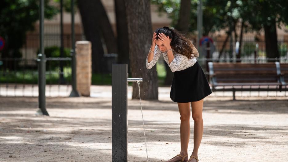 Una mujer se refresca en una fuente del parque Abelardo Sánchez, en Albacete.