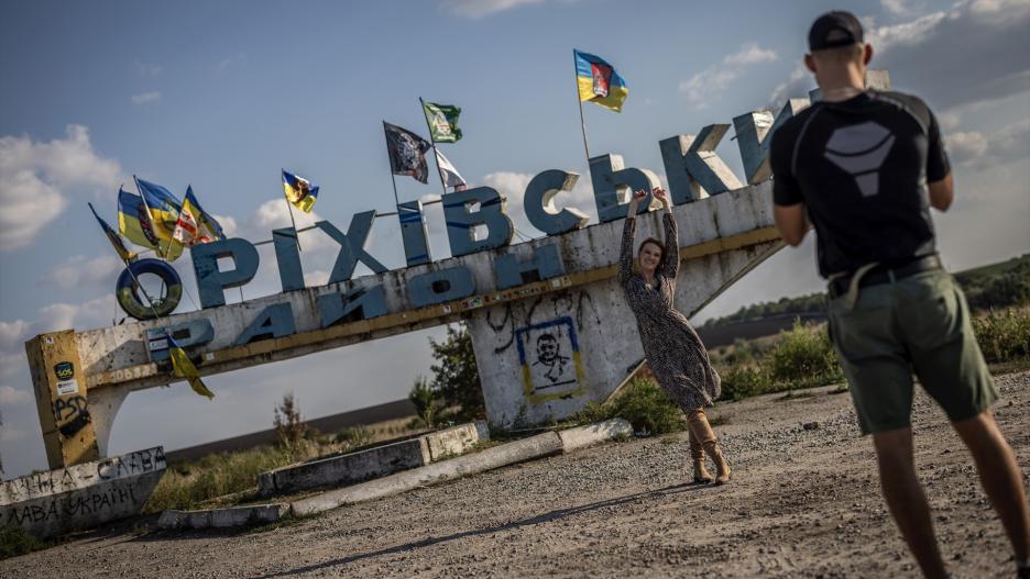 Una joven se presenta frente a un cartel cerca de la ciudad de Orikhiv, en primera línea. Casi nadie vive en la ciudad, que alguna vez tuvo casi 14.000 habitantes y se encuentra a pocos kilómetros del frente actual, y la mayoría de las casas están completamente destruidas o son inhabitables.
