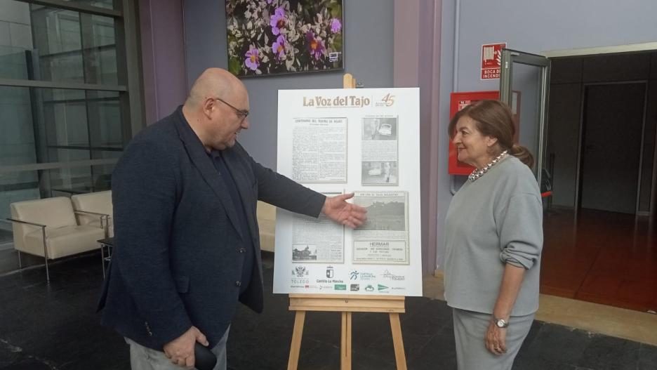 Alberto Retana, director de La Voz del Tajo, le muestra uno de los artículos de la exposición "Así Nació CLM" a Carmen Amores, Directora General de CMM.