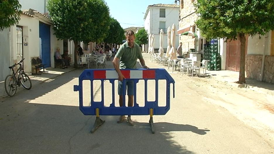 Operario municipal colocando una valla en una calle que da acceso al centro de Olmeda del Rey, en Cuenca