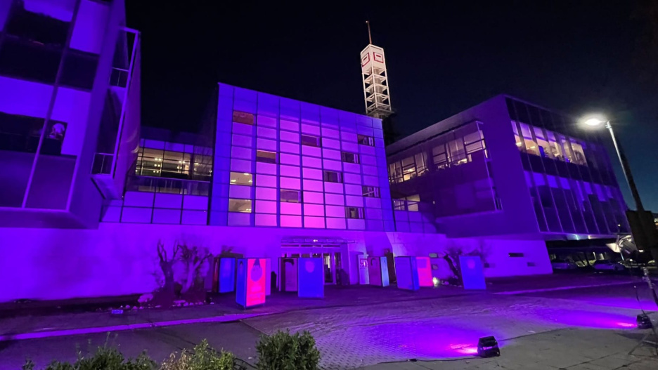 Fachada de CMM iluminada de color violeta el 25-N