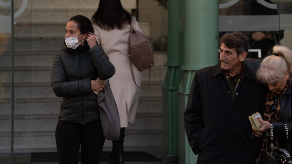 Varias personas con mascarillas a las puertas de un centro sanitario.