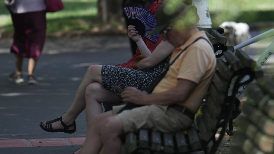 Varias personas se resguardan en la sombra en un parque-