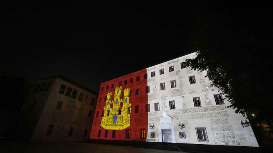 Fachada de las Cortes de Castilla-La Mancha iluminada con la bandera de la región.