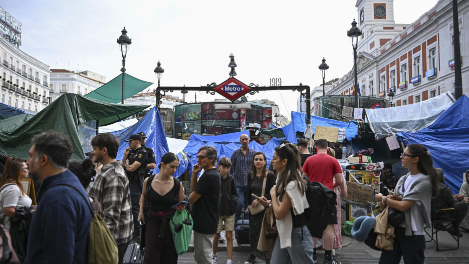 MADRID, 11/10/2026.- Varias personas salen de la estación de metro en la Puerta del Sol que continua rodeada de tiendas de campaña en Madrid.